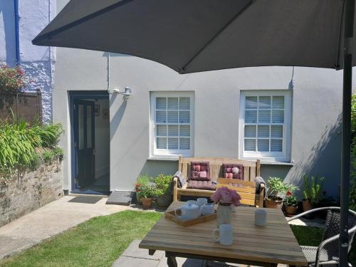 a table with an umbrella in front of a house at The Captain's House Charlestown St Austell in Charlestown
