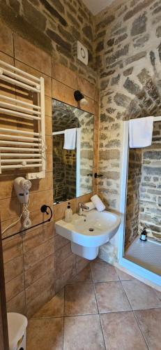 ein Badezimmer mit Waschbecken und einer Steinwand in der Unterkunft PASCHIERE by Keyhole Selection in Castelmezzano