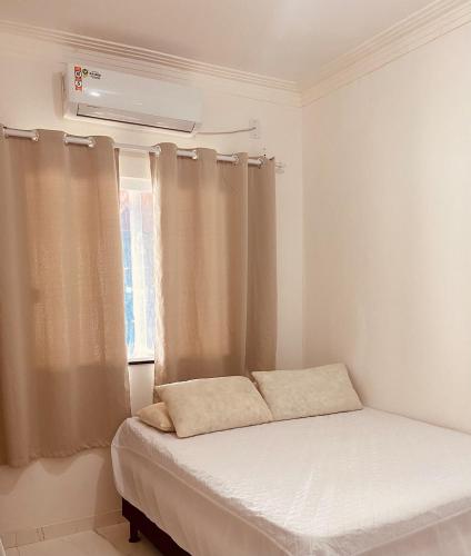 a bed in a room with a window with curtains at Casa Arembepe 2 in Camaçari