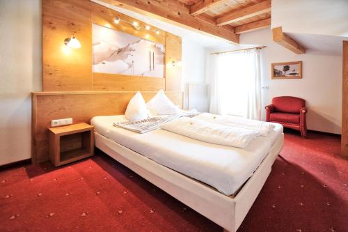 a bedroom with a large white bed and a chair at Hotel Traube in Fliess