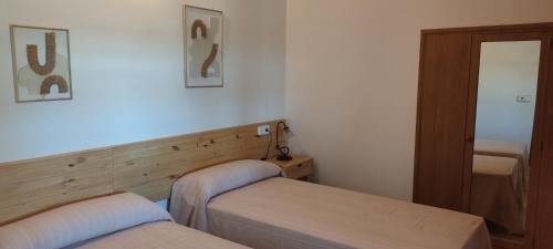 a small bedroom with two beds and a mirror at Finca Blanca Formentera in Sant Francesc Xavier