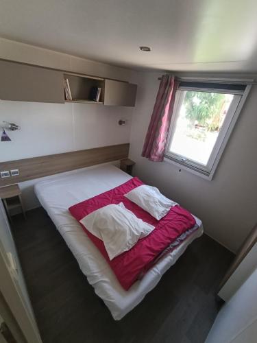 a small bedroom with a bed with a window at Mobil'home Valras in Valras-Plage