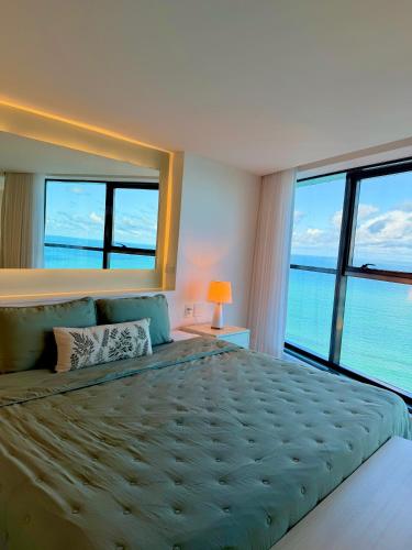 a bedroom with a large bed with a view of the ocean at Refuge Beira Mar - Boa Viagem in Recife