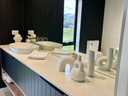 a bathroom with two sinks and vases on a counter at Luxury Mountain View Retreat in Frankton
