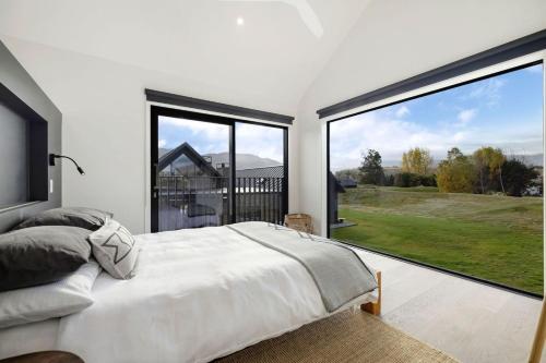 a bedroom with a bed and large windows at Luxury Mountain View Retreat in Frankton
