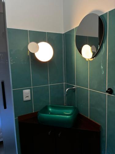 a green bathroom with a sink and a mirror at Pousada dos Bougainvilles in Manhã