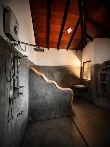 a shower in a bathroom with a wooden ceiling at Kabalana Surf Hostel in Ahangama