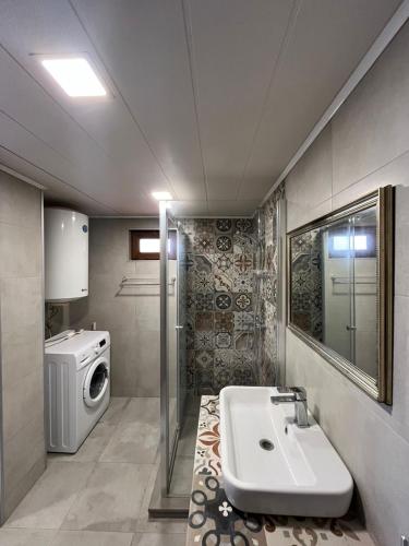 a bathroom with a sink and a washing machine at Deluxe Family Stay Near The Beach in Kvariati