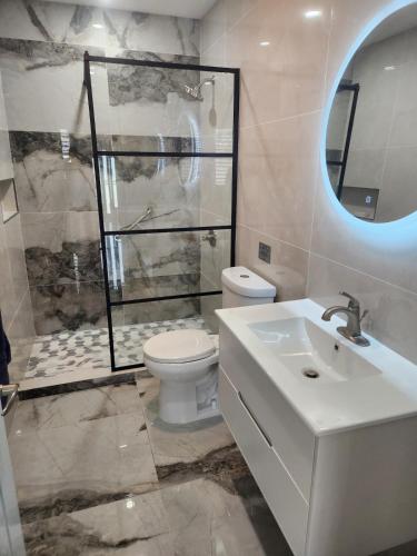 a bathroom with a toilet and a sink and a shower at 2BR Apartment, Blue Ocean Suites, Manati in Manati