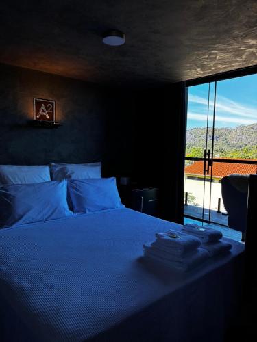 a bedroom with a bed with blue sheets and a window at Pousada dos Bougainvilles in Manhã