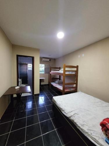 a room with two beds and a desk and a table at Cantinho do Mar in Bertioga