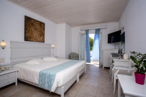 a bedroom with a bed and a desk and a television at Yiannaki Hotel in Ornos