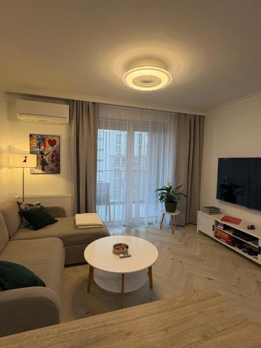 a living room with a couch and a tv and a table at Luksusowy Apartament Onyks - Parking Gratis in Suwałki