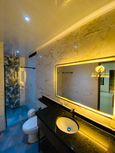 a bathroom with a sink and a mirror and a toilet at Hotel Colonial Sol y Luna in Paz de Ariporo