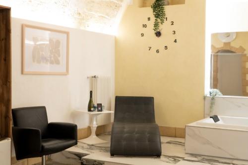 ein Wohnzimmer mit einem Sessel und einer Uhr an der Wand in der Unterkunft QUART0 GREC0 Suite 15 in Altamura