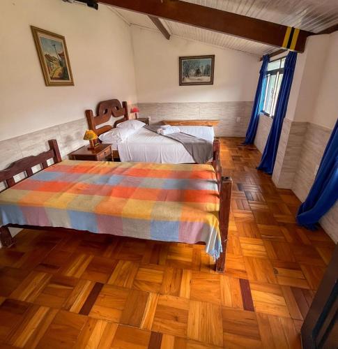 a bedroom with two beds and a wooden floor at Pouso do Elefante in Serra do Cipo