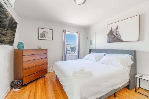 a bedroom with a large white bed with a wooden dresser at Midtown Sanctuary w Pac-Man in Reno