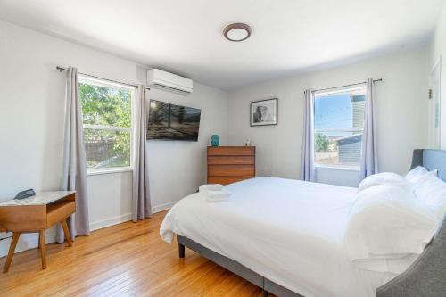 a white bedroom with a bed and two windows at Midtown Sanctuary w Pac-Man in Reno