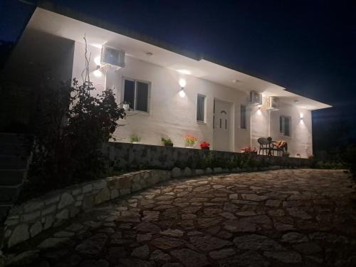 a white house at night with a stone driveway at Damiano House in Sarandë