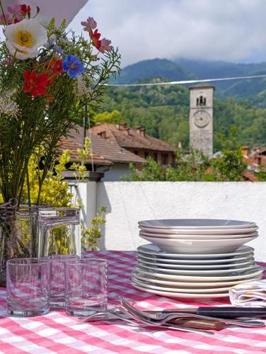 a table with plates and glasses and a vase of flowers at Da Anny - Valdilana in Coggiola