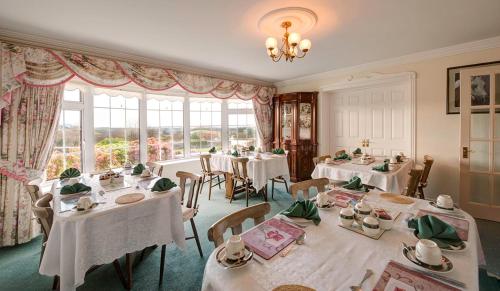 a dining room with white tables and chairs and windows at Carrabaun House in Westport