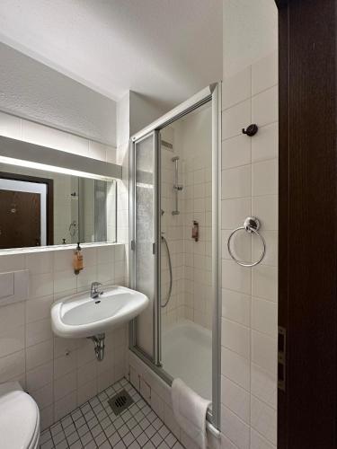 a white bathroom with a shower and a sink at Hotel Astor in Wuppertal