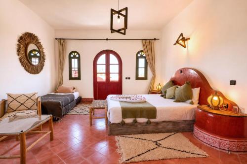 a bedroom with a large bed and a couch at Villa Nouran - Chambre D'Hôte in Ghazoua