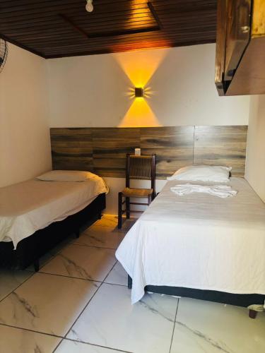 a bedroom with two beds and a chair at Hotel Pousada Don Ruan in Ponta Grossa
