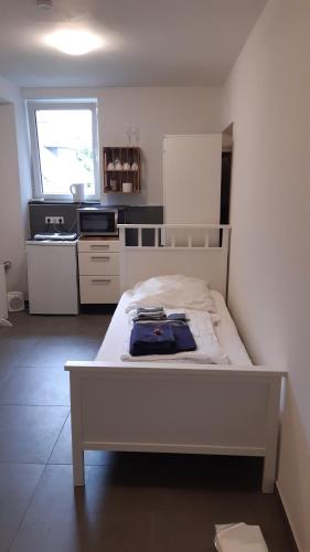 a white bed in a room with a kitchen at Zimmer auf Bauernhof in Kürten