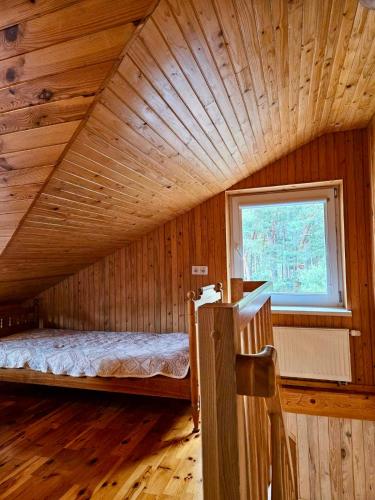 a bedroom in a log cabin with a bed and a window at Pas Aldoną in Šventoji
