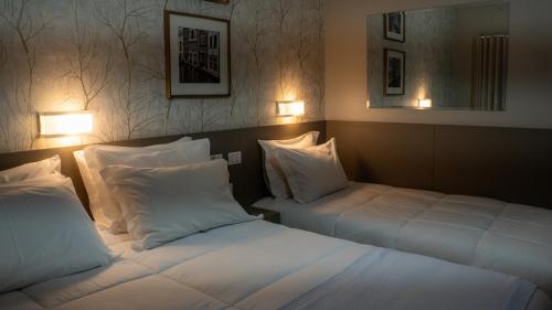two beds in a hotel room with white pillows at Nohotel Nova Odessa in Nova Odessa