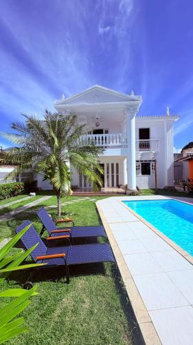 a villa with a swimming pool and blue lounge chairs at Terra do Sol Pousada - Passarela in Porto Seguro