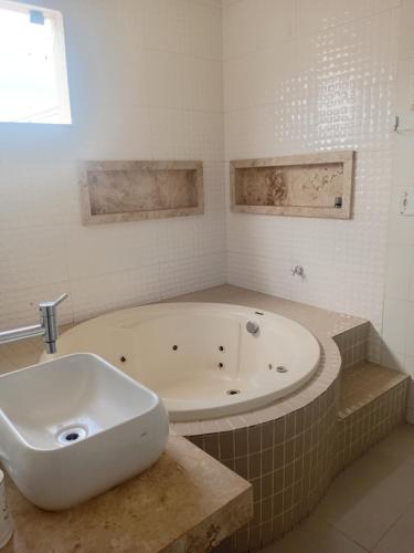 a bathroom with a large tub and a sink at Refúgio Urbano Amplo e Luxuoso in Imperatriz