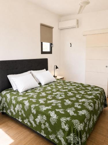 a bedroom with a bed with a green and white blanket at Au Petit Bungalow - Air conditionned & Mountain view in Moorea