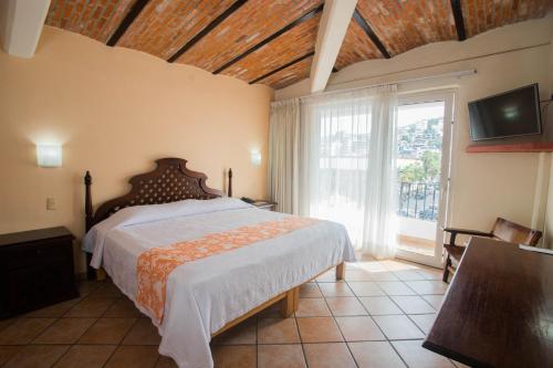 a bedroom with a bed and a large window at Hotel El Pescador in Puerto Vallarta