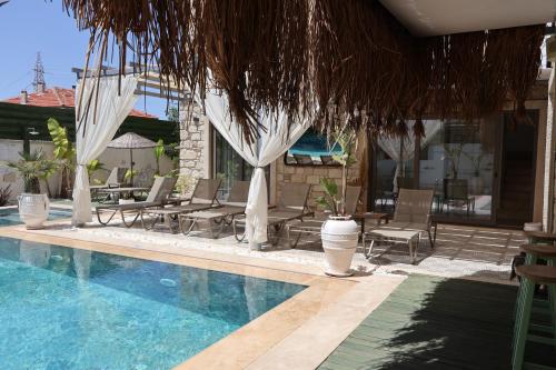 a pool with chairs and umbrellas next to a house at My Angels Alaçatı in Alaçatı