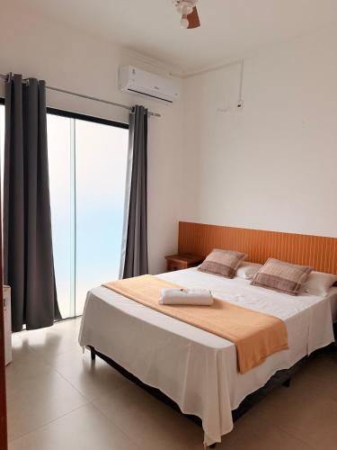 a bedroom with a large bed and a large window at Pouso Mineiro in São João Batista do Glória