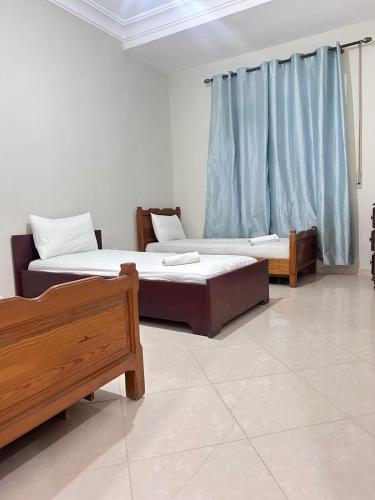 two beds in a room with blue curtains at Rmilate Coast Apartment in Asilah