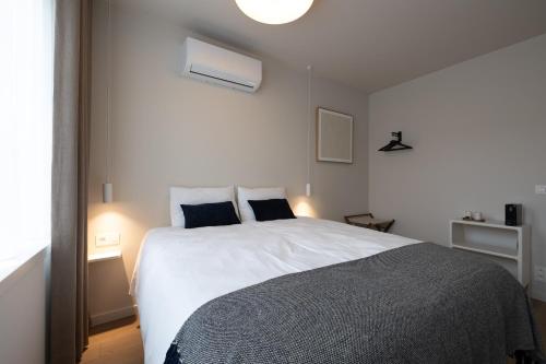 a bedroom with a large white bed with blue pillows at Maison Dieu in Hasselt