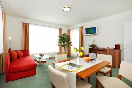 a living room with a table and a red chair at Pension Klug Adults only - DorfResort Mitterbach in Mitterbach