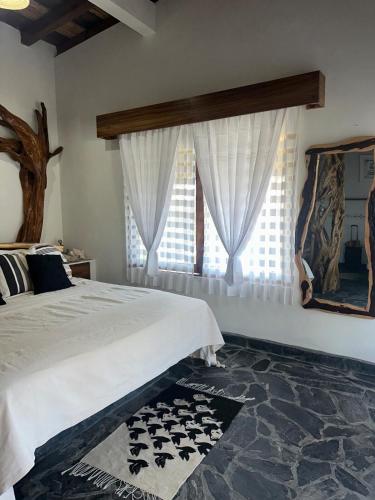 a bedroom with a large bed with white curtains at Casa Mario Alberto - Oceanfront Bungalows in Puerto Ángel
