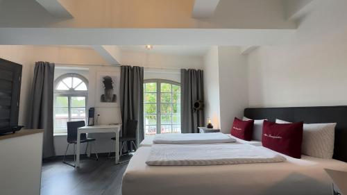 a bedroom with two beds with red pillows and a desk at Alter Kornspeicher in Havelberg