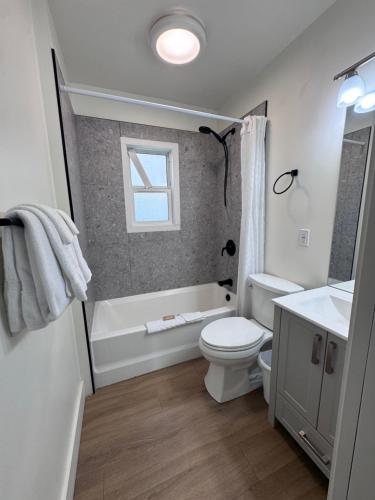 a bathroom with a toilet and a tub and a sink at Shoreline Resort Condominiums in Penticton