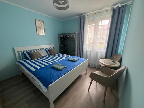 a blue bedroom with a bed and a chair at Przystanek Hel in Hel