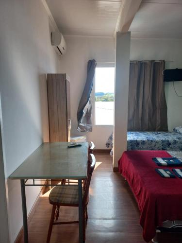 a room with a table and a bed and a window at Hotel Status in Jaguarão