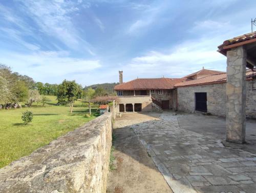 an external view of a house with a stone wall at Casa da Torreira Naturaleza y descanso in Galegos