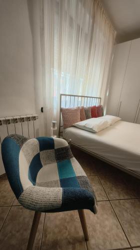 a bedroom with a bed and a chair next to a window at SISTERS GUEST HOUSE 2 in Somma Lombardo