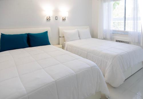 two beds in a room with white and blue at Palm Breeze Hotel in Lake Worth