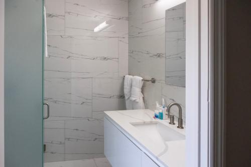 a white bathroom with a sink and a mirror at Palm Breeze Hotel in Lake Worth