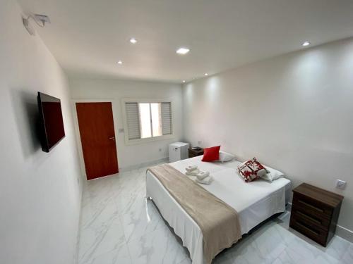 a white bedroom with a bed and a television at Suíte com Jacuzzi Vista de Escarpas 4 in Capitólio